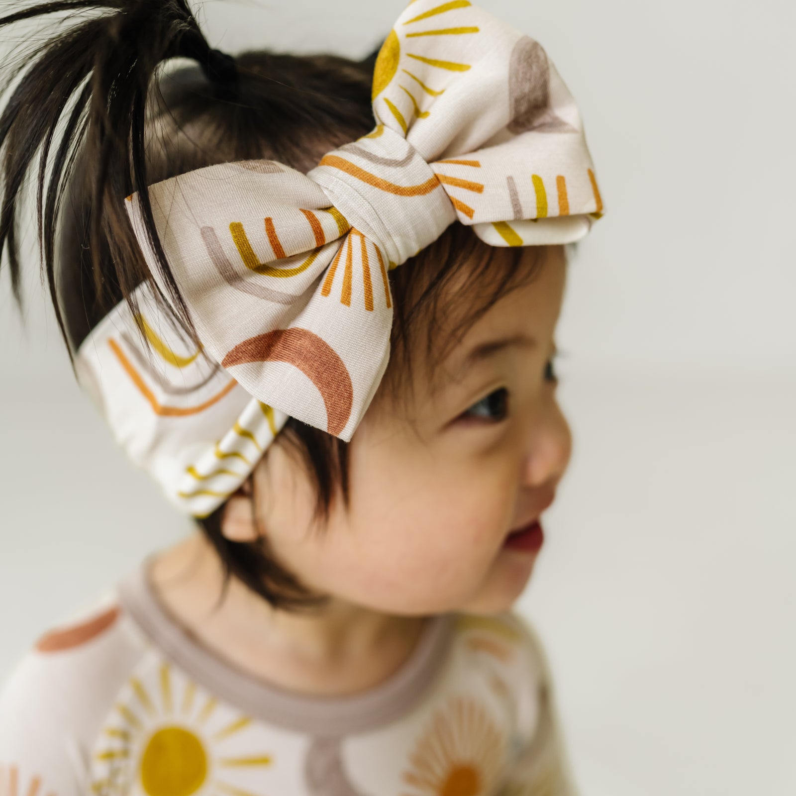 Profile view of a child wearing a Desert Sunrise luxe bow headband