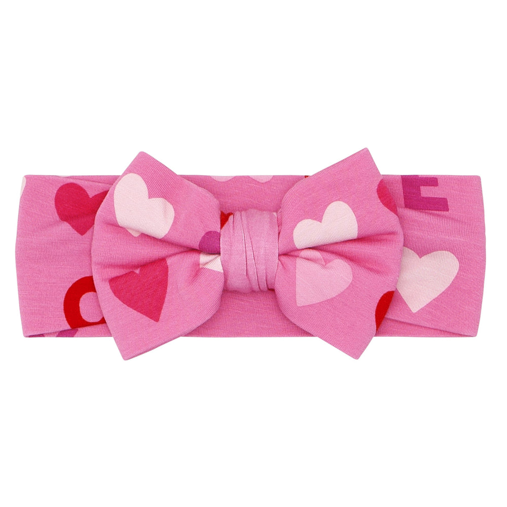 Click to see full screen - Flat lay image of a Pink XOXO luxe bow headband in size newborn to age 3