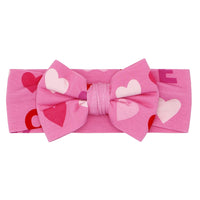 Flat lay image of a Pink XOXO luxe bow headband in size newborn to age 3