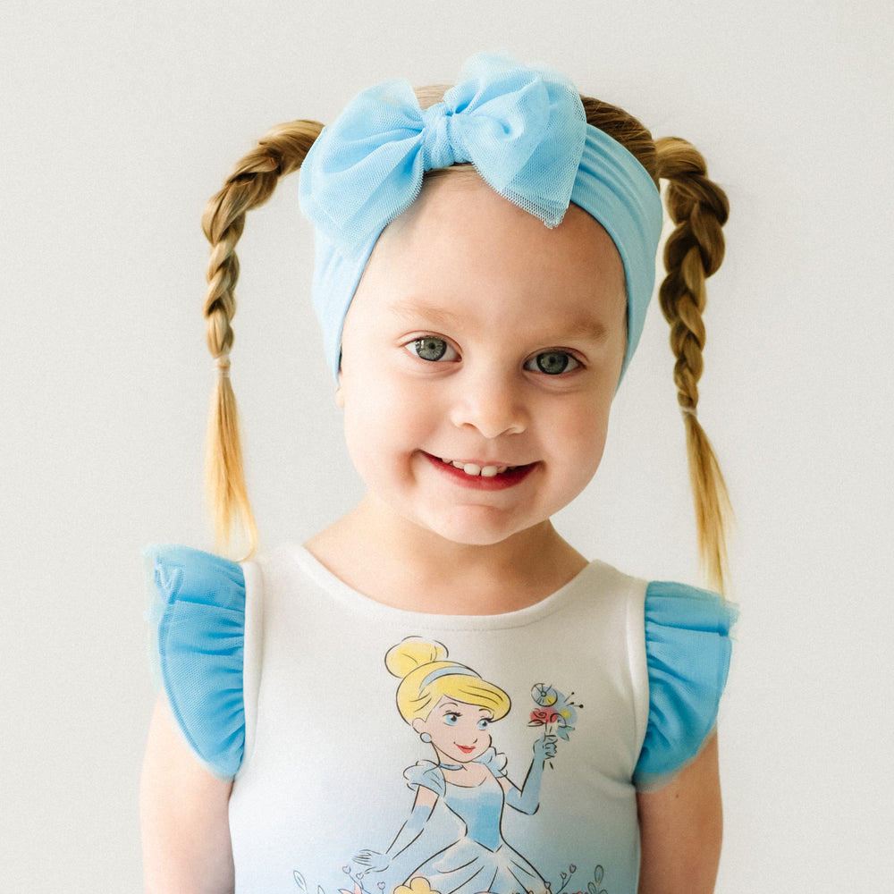 Close up image of a child wearing a Cinderella flutter tiered tutu dress with bloomer and matching tulle luxe bow headband