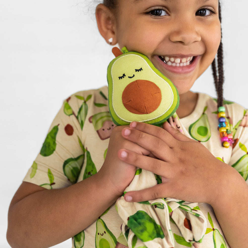 Alternate close up image of a child holding up a Guac the Avocado sleepyhead lovey