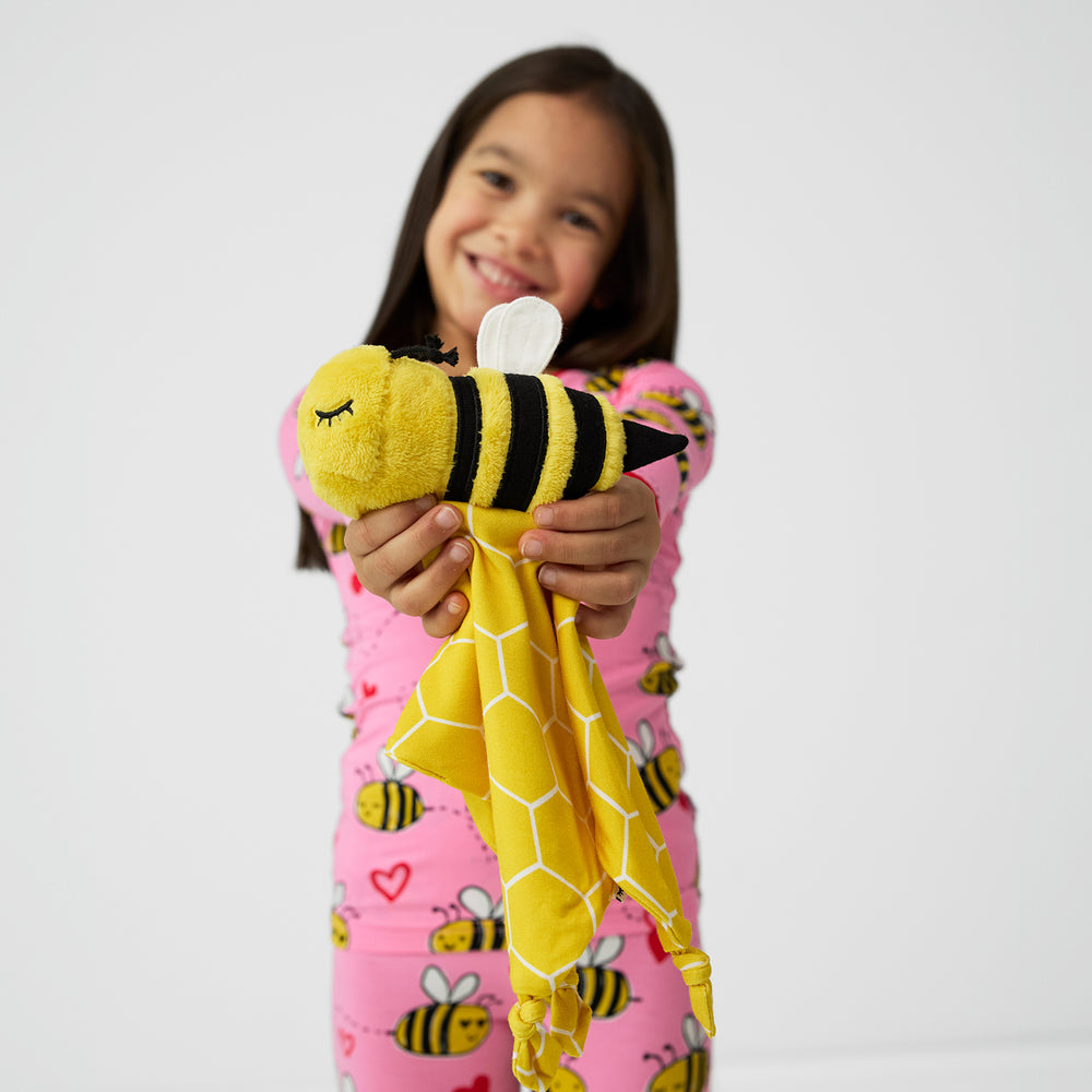 Alternate image of a child holding up a Honey the Bumble Bee lovey 