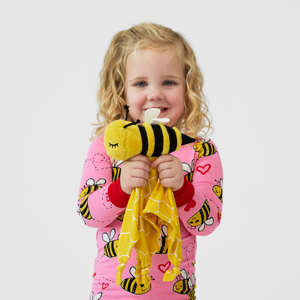 Image of a child holding up a Honey the Bumble Bee lovey 