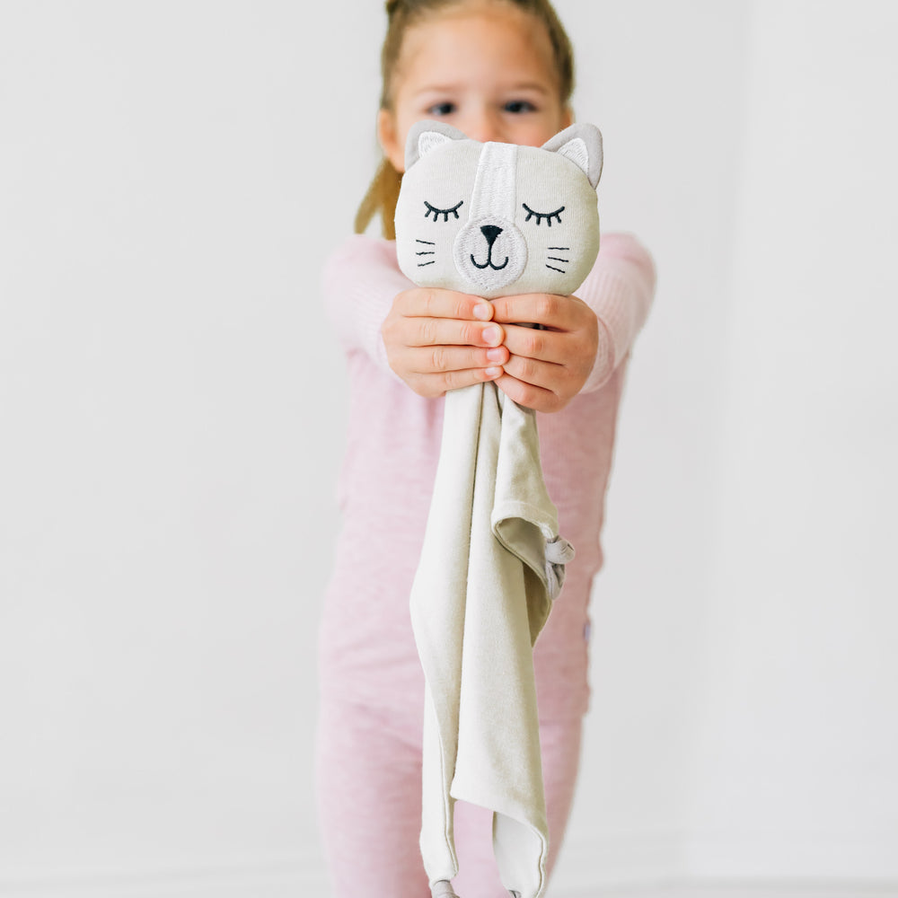 Child holding up a Clementine the Cat lovey 