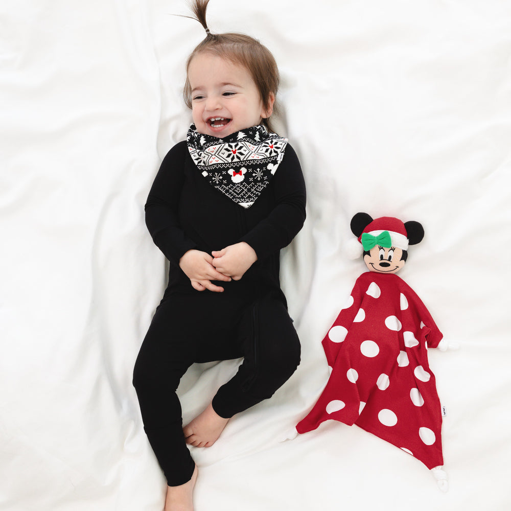 Child wearing a Mickey Fair Isle bib over a black zippy next to a Minnie lovey