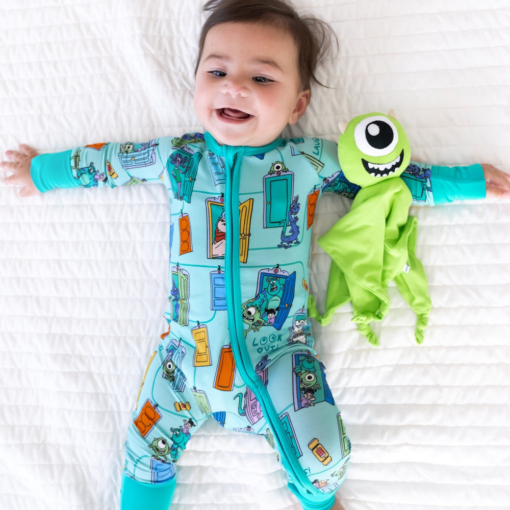 Top view image of baby laying down next to the Disney Monsters, Inc. Mike Wazowski Lovey