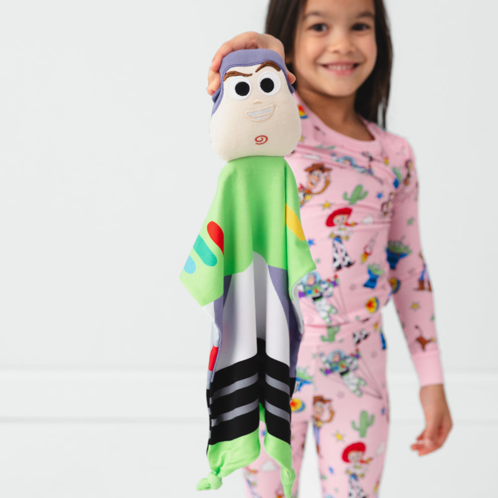 Image of a child holding out a Buzz Lightyear Lovey wearing Toy Story Stars pjs