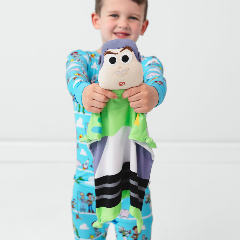 Image of a child holding out a Buzz Lightyear Lovey wearing Toy Story Pals pjs