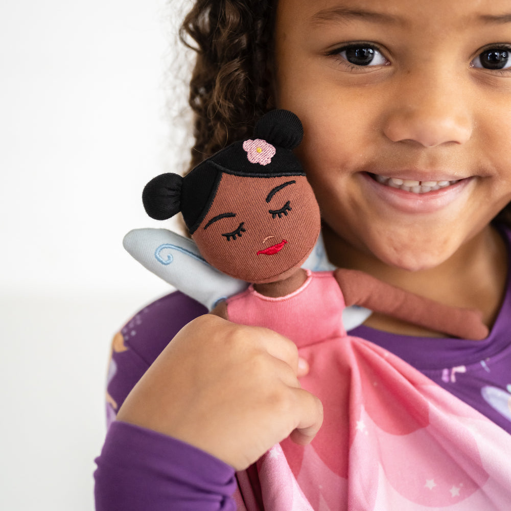 Close up image of smiling girl holding the Flora the Pink Fairy Sleepyhead Lovey