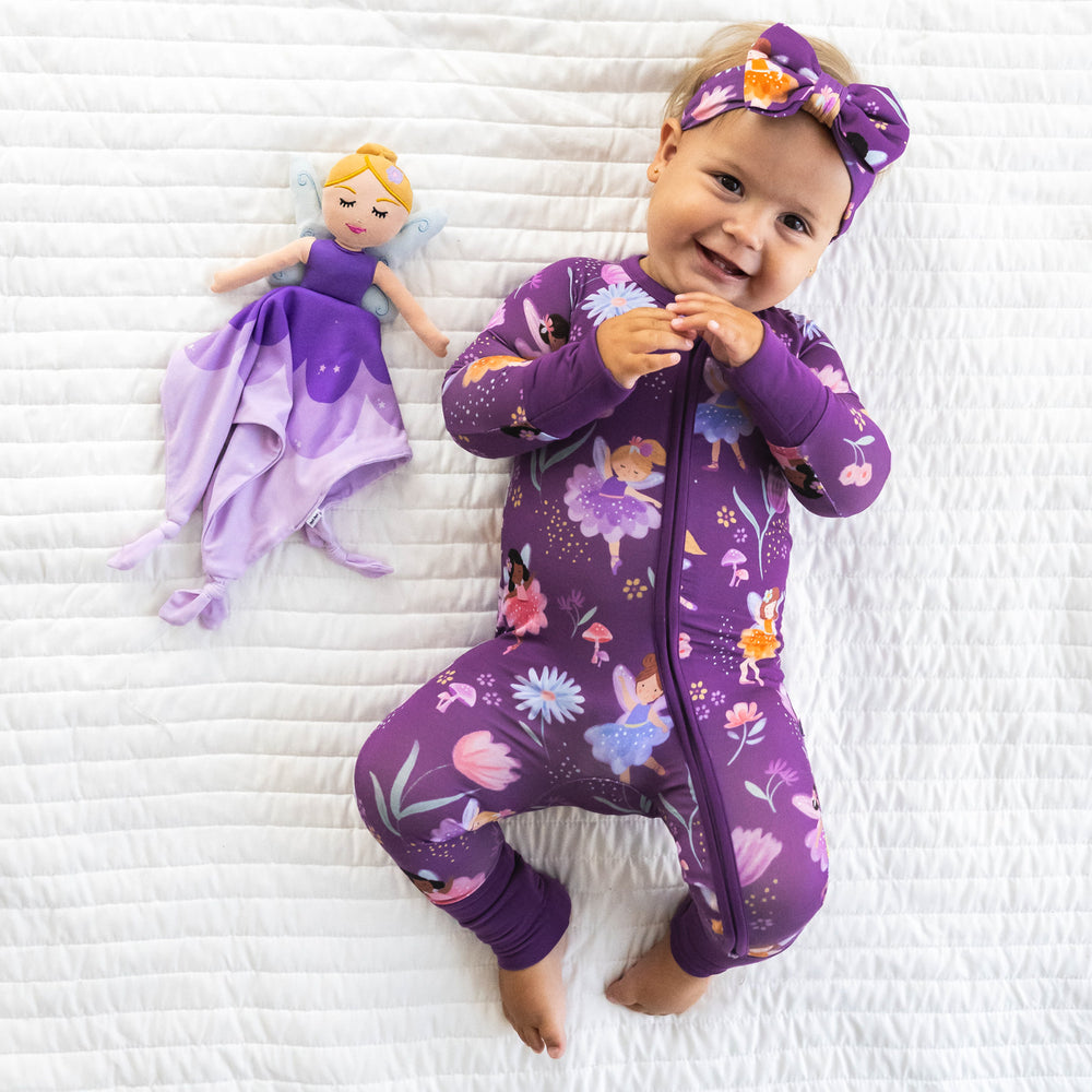 Top view image of baby laying down while wearing the Purple Fairy Zippy and next to the Fiona the Purple Fairy Sleepyhead Lovey