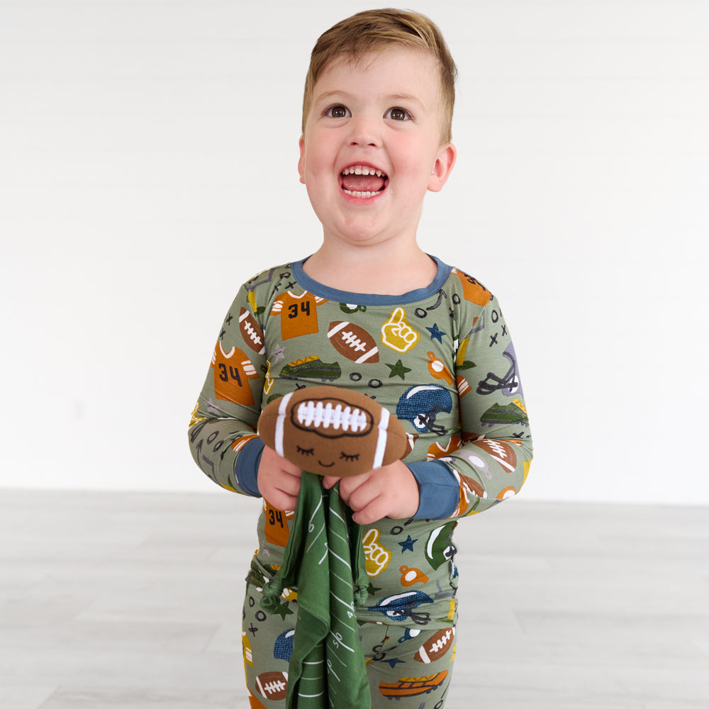 Child holding the travis-the-touchdown-football-sleepyhead-lovey, wearing the Touchdown Time Two-piece Pajama Set