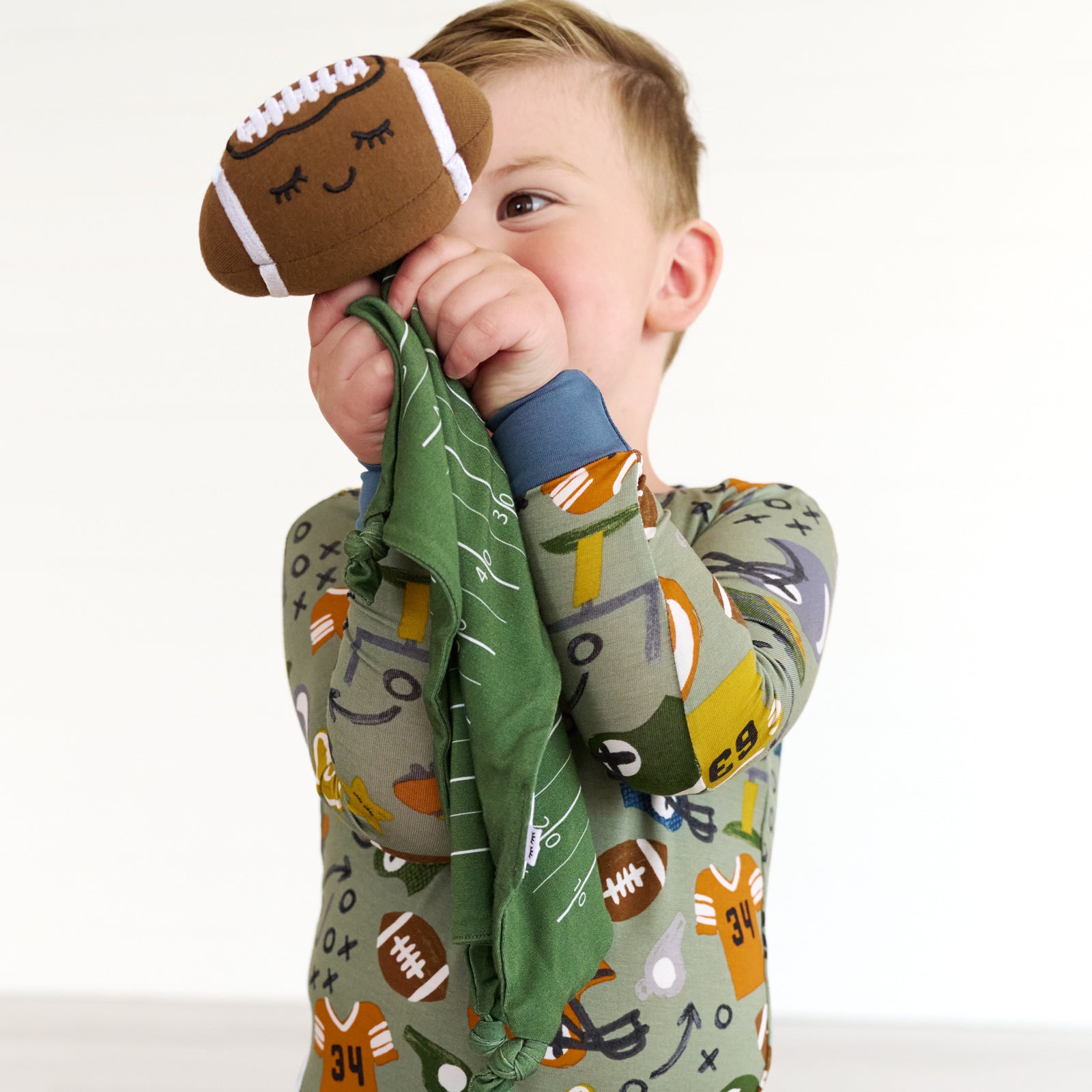 Alternative close up image of a child holding the travis-the-touchdown-football-sleepyhead-lovey