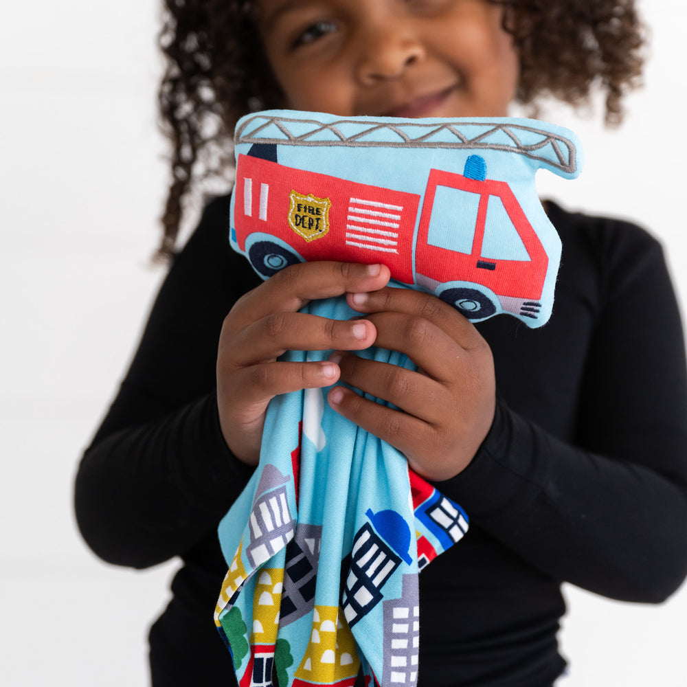 Close up image of a child holding out a Franklin the Firetruck sleepyhead lovey