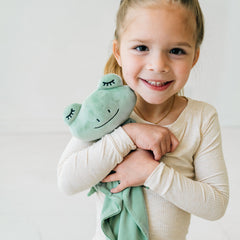 Child cuddling their Fredrik the Frog lovey wearing a Heather Oatmeal two piece pj set