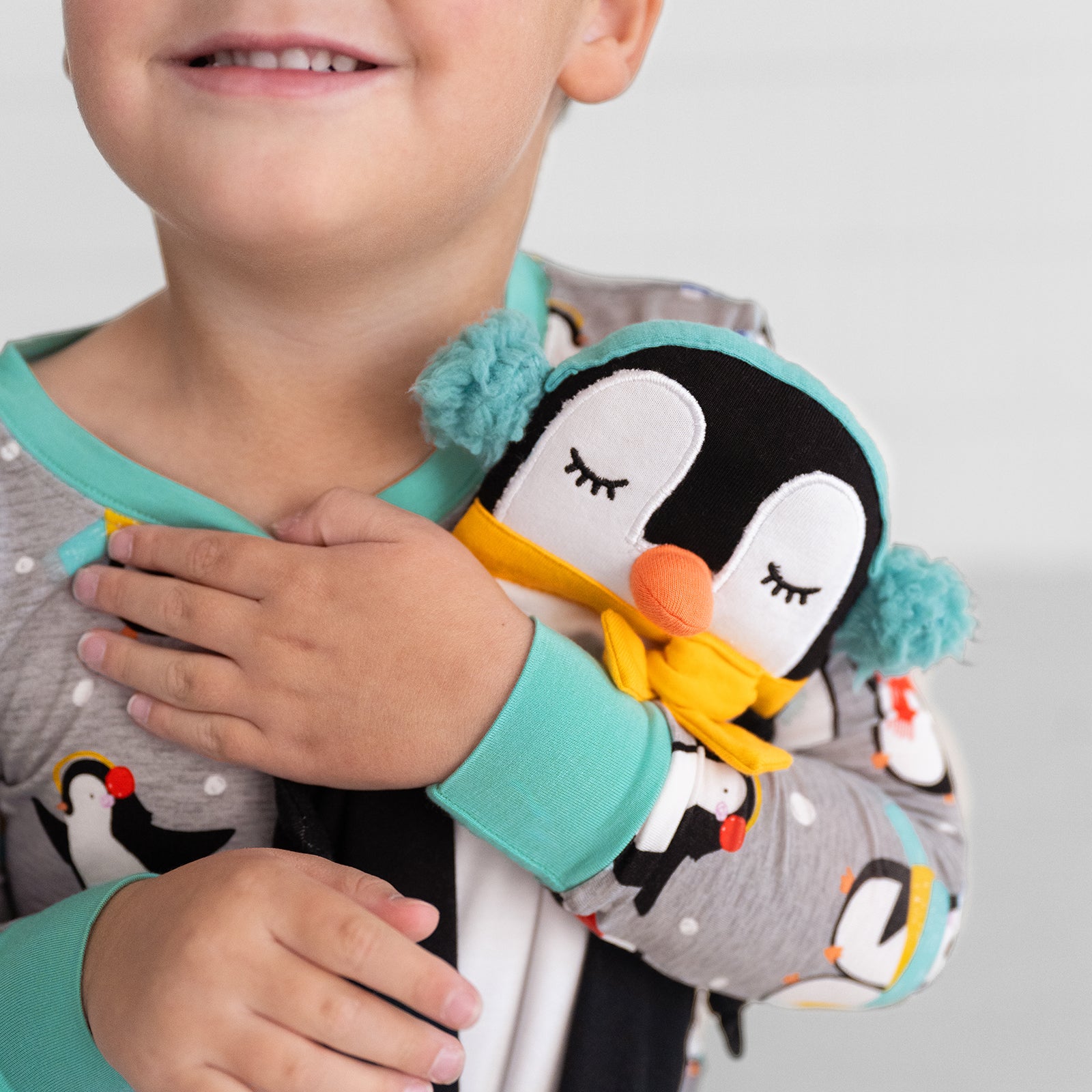 close up image of a child holding a Tux the penguin lovey