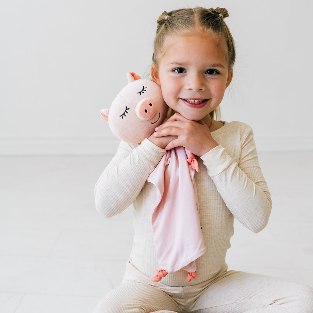 Child hugging a Pennie the Pig lovey