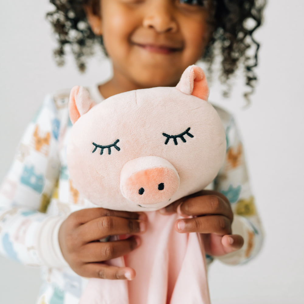 Close up image of a child holding a Pennie the Pig lovey