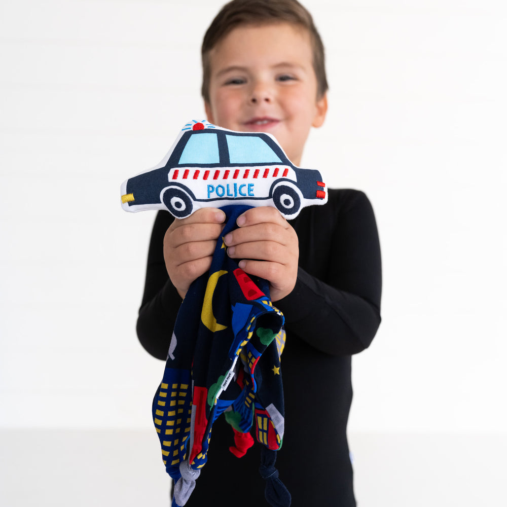 Alternate close up image of a child holding up a Polly the Police Car sleepyhead lovey