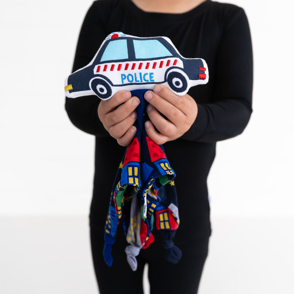 Close up image of a child holding a Poly the Police Car sleepyhead lovey