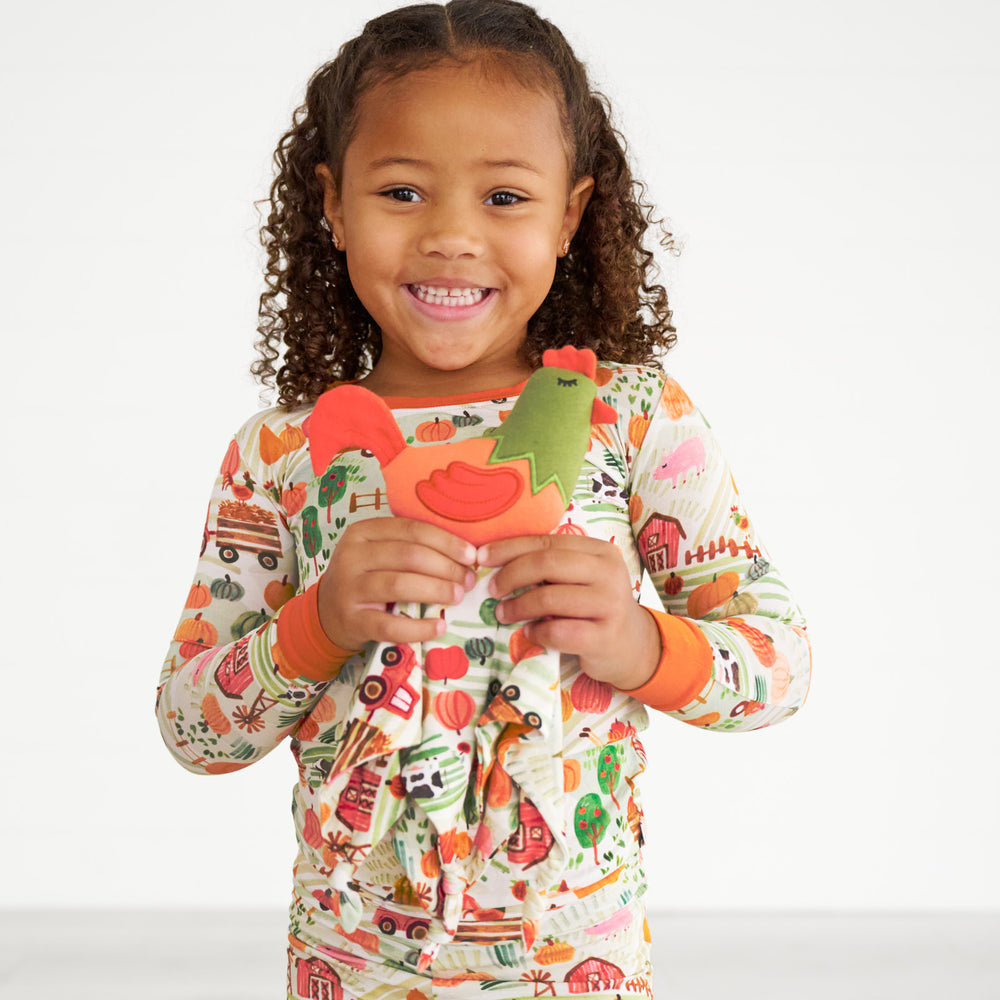 Child wearing Happy Harvest pjs with a Rocky Rooster sleepyhead lovey