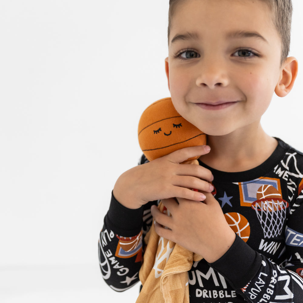 Child cuddling Hoops the Basketball Sleepyhead Lovey wearing matching Slam Dunk pajamas