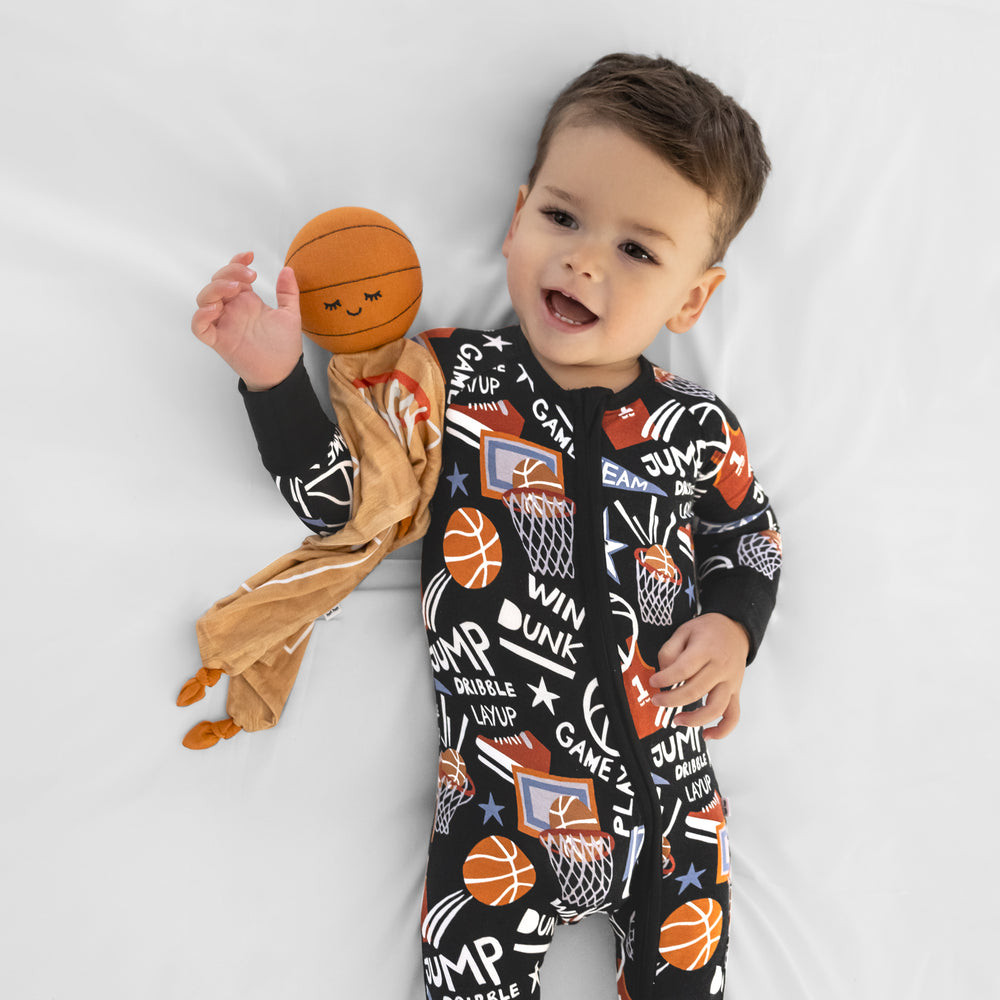 Child laying with Hoops the Basketball Sleepyhead Lovey wearing matching Slam Dunk pajamas