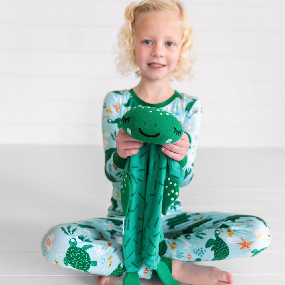 Image of a child holding up a Tilly the Turtle sleepyhead lovey