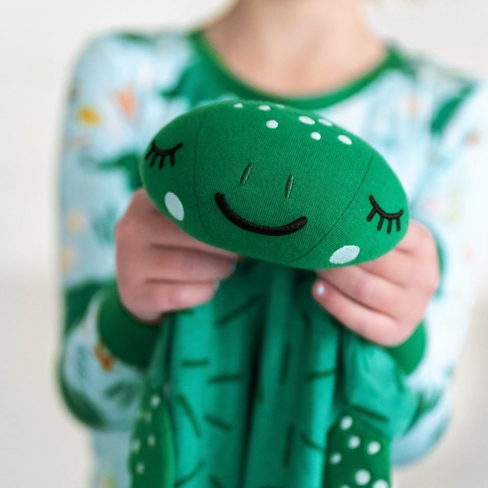 Close up image of a child holding up a Tilly the Turtle sleepyhead lovey