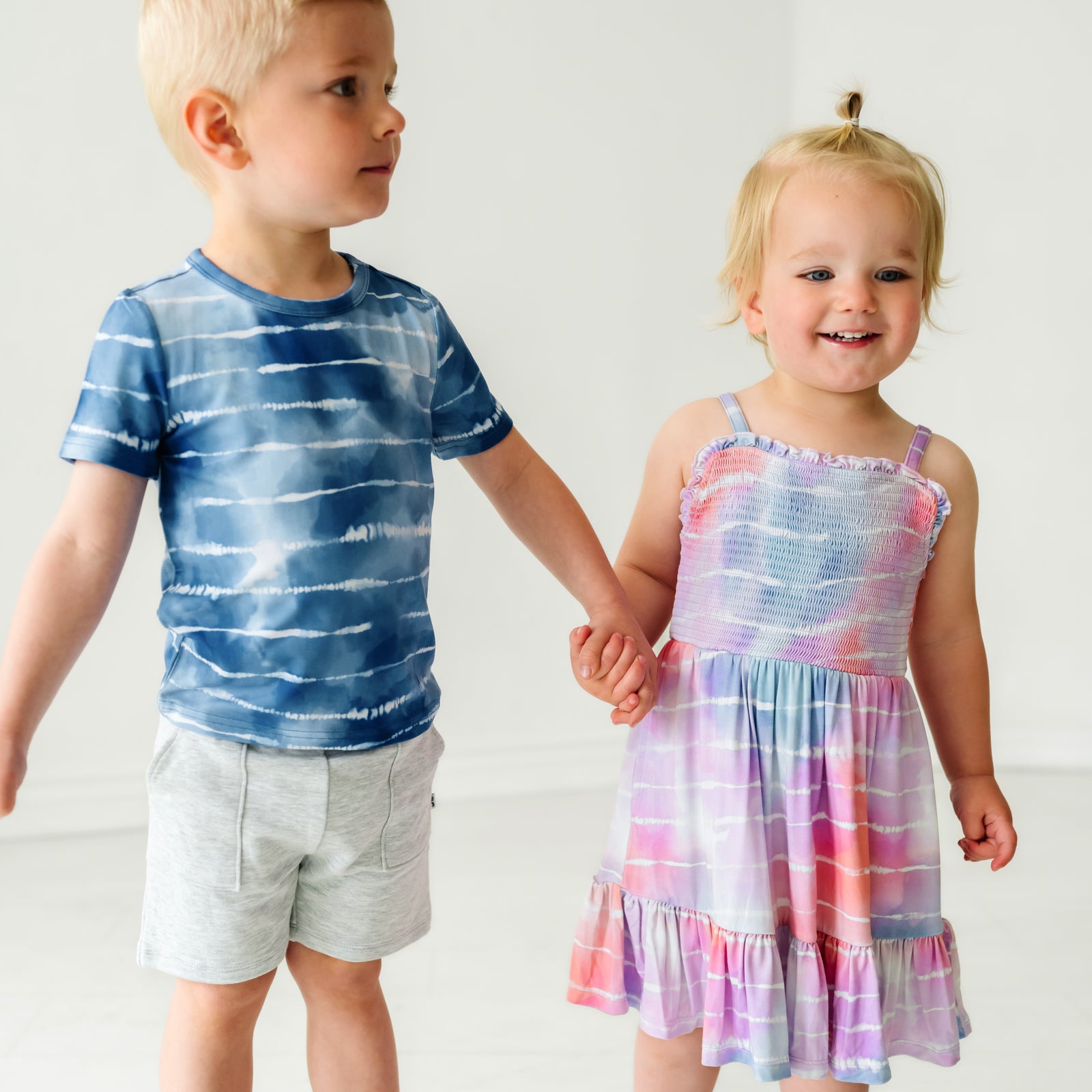 Two children holding hands wearing coordinating Tie Dye Dreams Play outfits