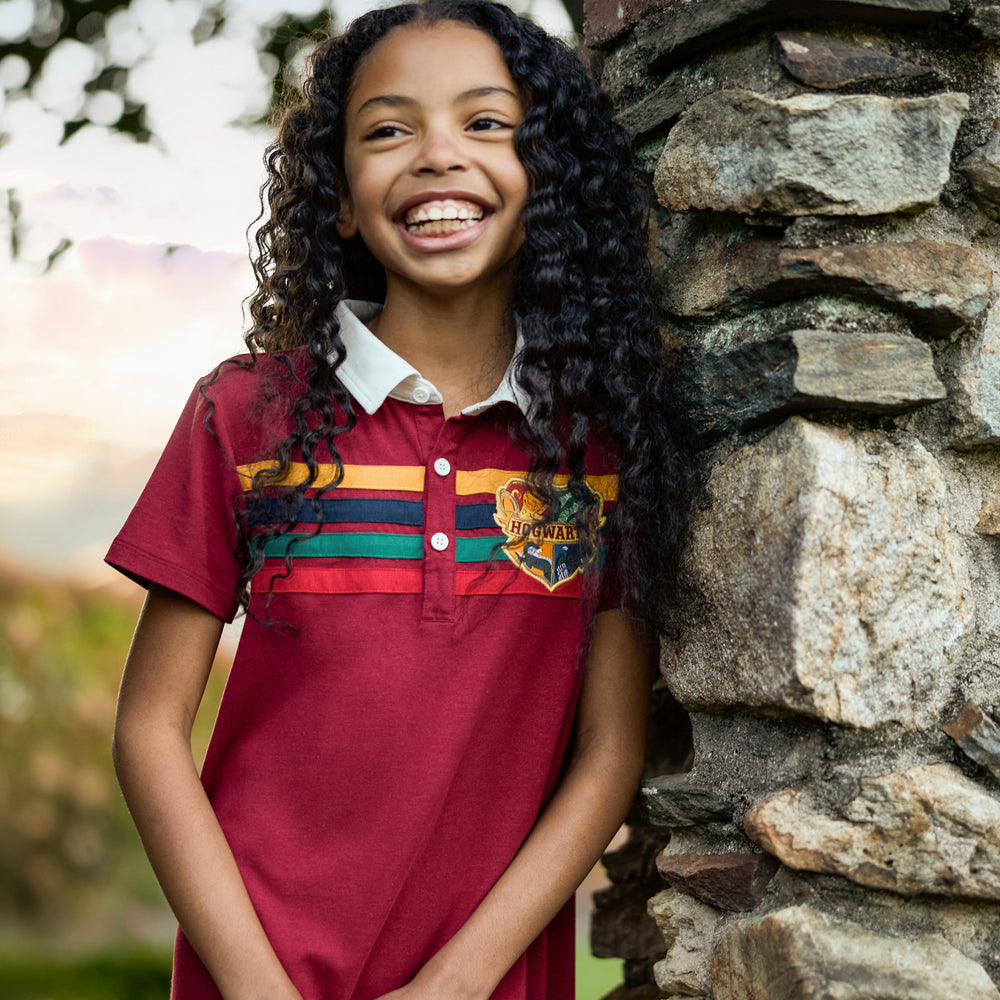 Image of a child leaning against a stone wall wearing a Harry Potter Rugby Dress