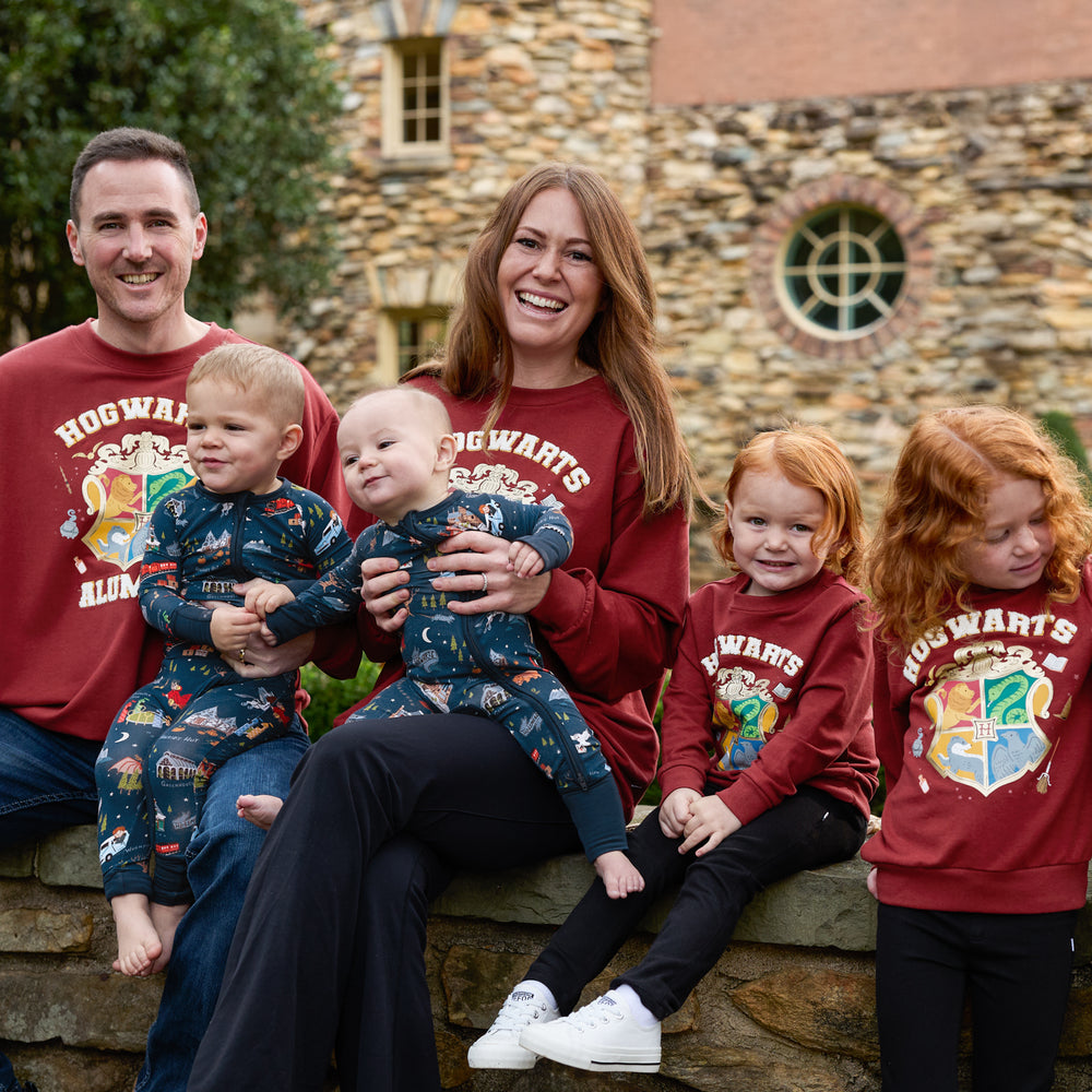 family of six wearing matching Harry Potter themed crewnecks. children on mom's lap are wearing an Evening At Hogwarts printed zippies