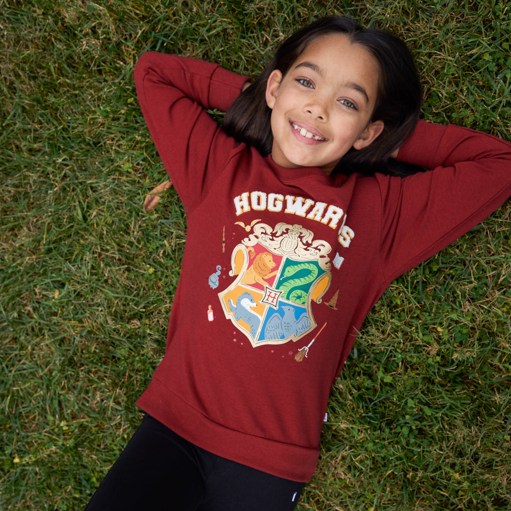 Image of a child laying on grass wearing a Hogwarts Crewneck Sweatshirt