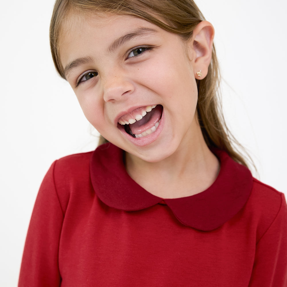 Close up image of a child wearing a Holiday Red Collar Pocket Dress