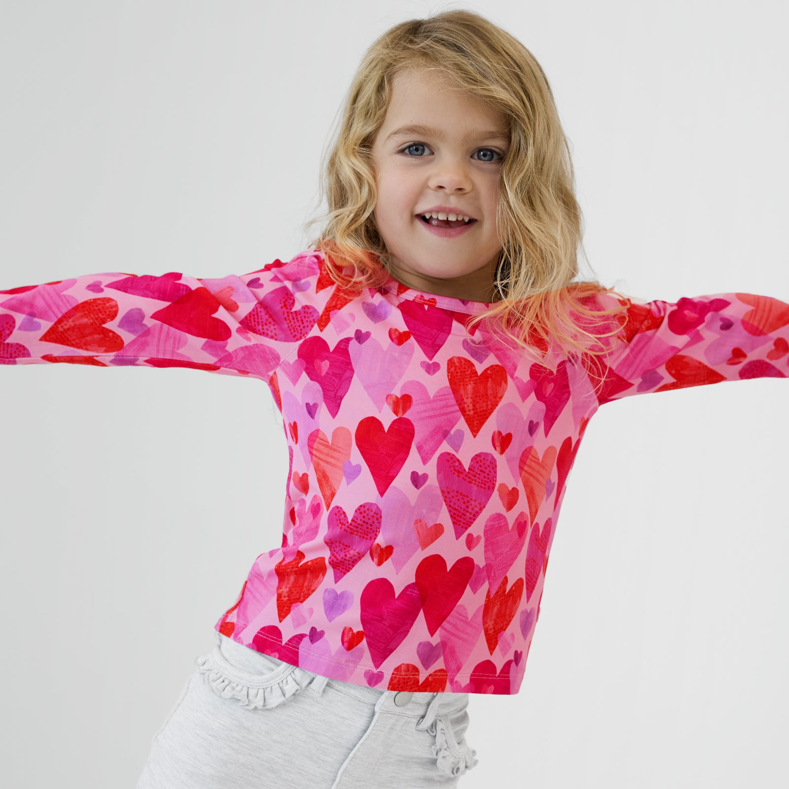 Close up of a child with their arms out wearing a Pink Hearts & Crafts Puff Sleeve Tee and coordinating pants