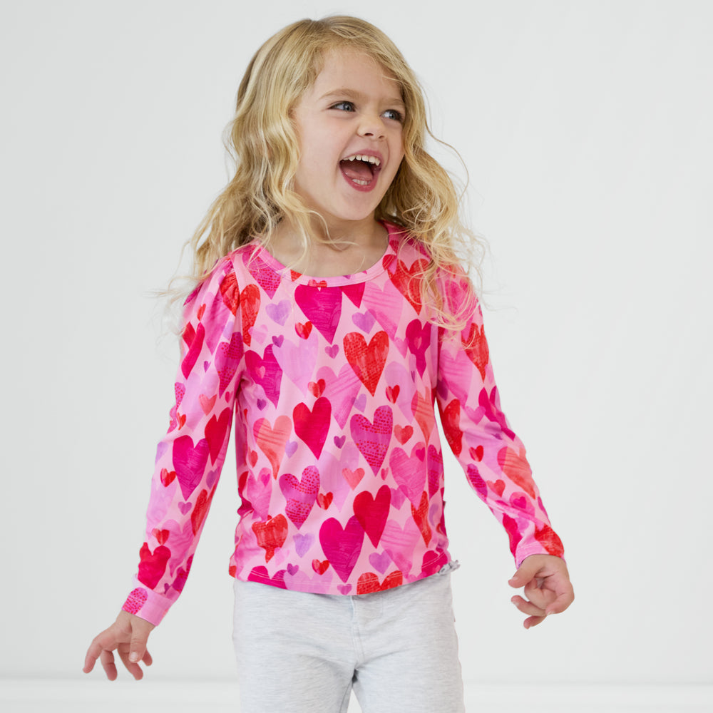 Laughing child wearing a Pink Hearts & Crafts Puff Sleeve Tee and coordinating pants