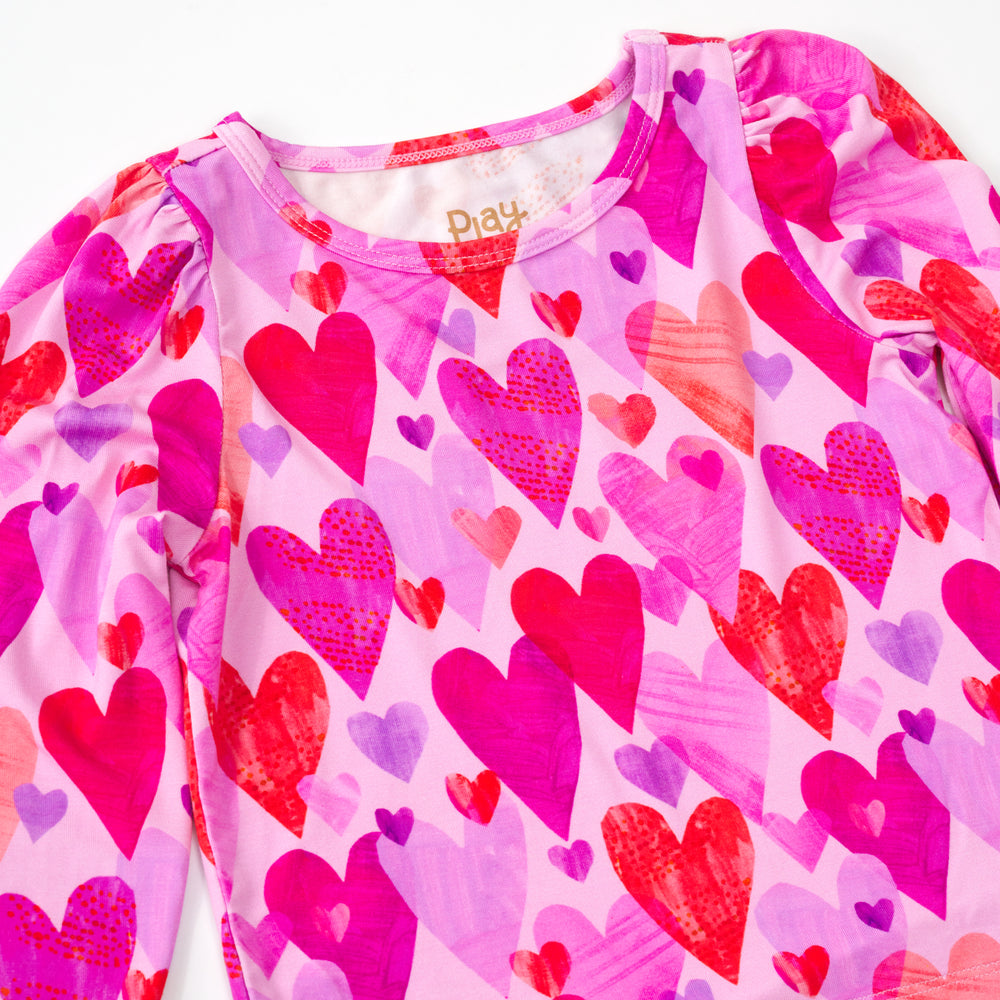 Close up flat lay of a pink hearts & crafts puff sleeve bodysuit