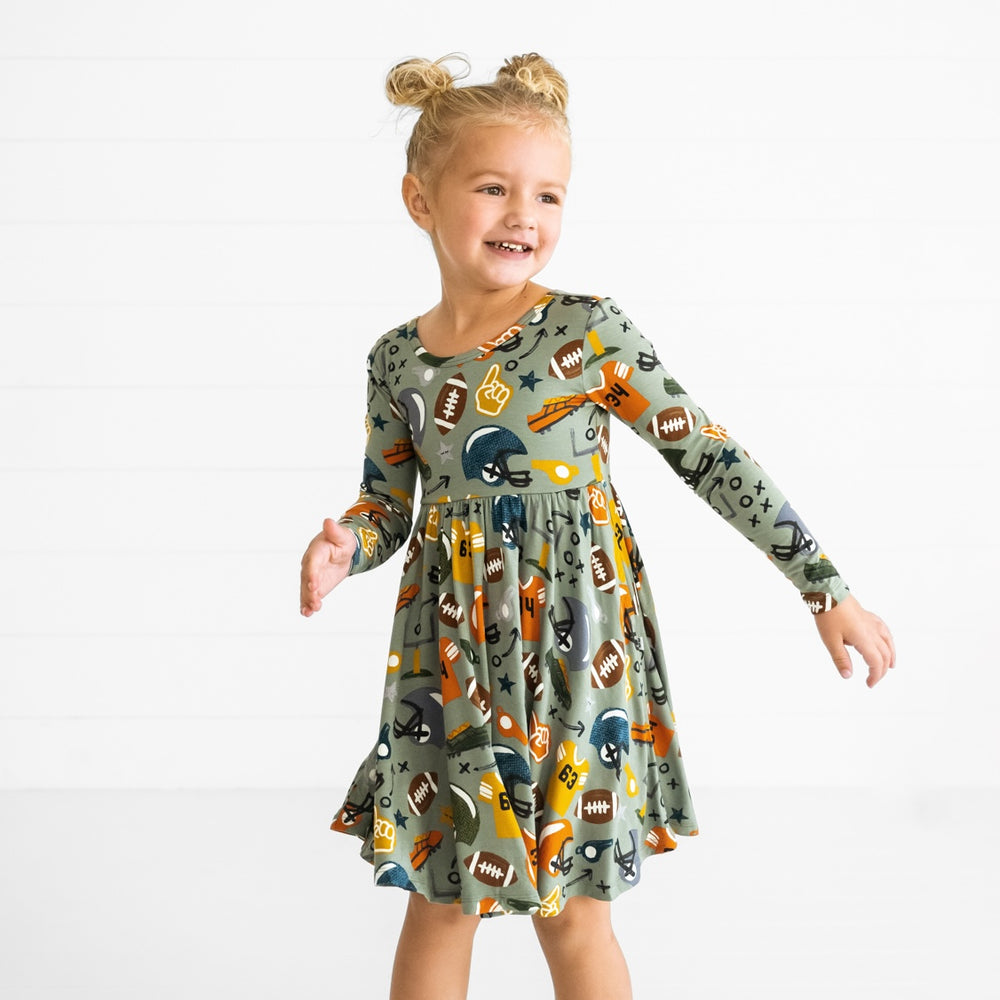 Image of a child spinning around wearing a Touchdown Time Twirl Dress