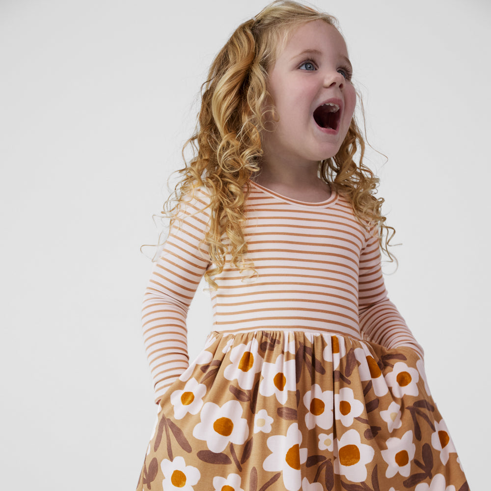 Child looking to the side with her hands in the pockets of a Daisy Daydream long sleeve twirl dress