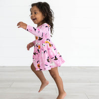 Girl playing while in the Pink Glowing Ghouls Twirl Dress with Bodysuit