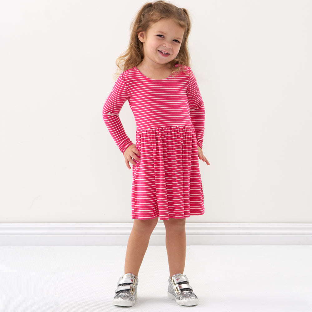 Click to see full screen - Child with her hands on her hips wearing a Pink Punch Stripes bow back skater dress