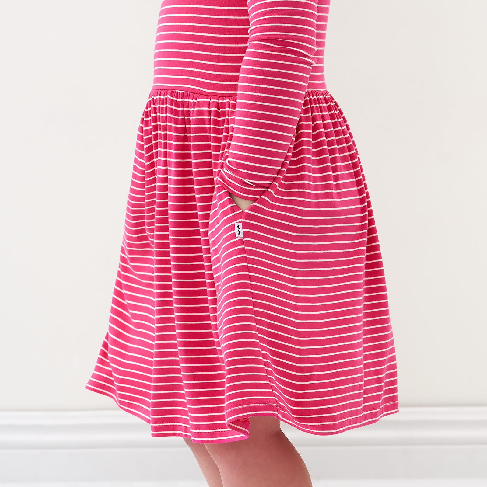 Close up image of a child wearing a Pink Punch Stripes bow back skater dress detailing the pocket