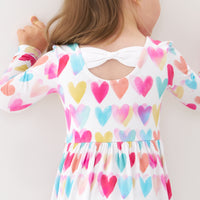 Back view image of a child wearing a Watercolor Love bow back skater dress detailing the bow back
