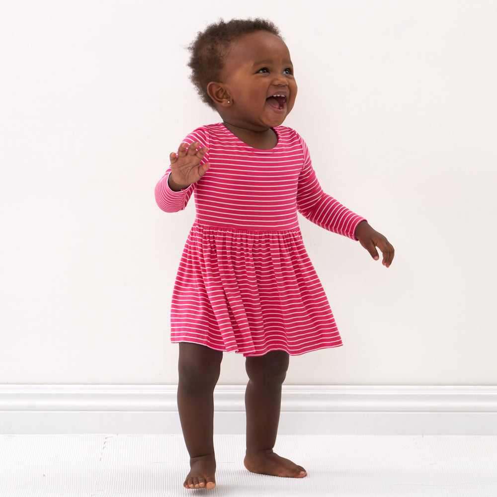 Click to see full screen - Child laughing wearing a Pink Punch Stripes bow back skater dress with bodysuit