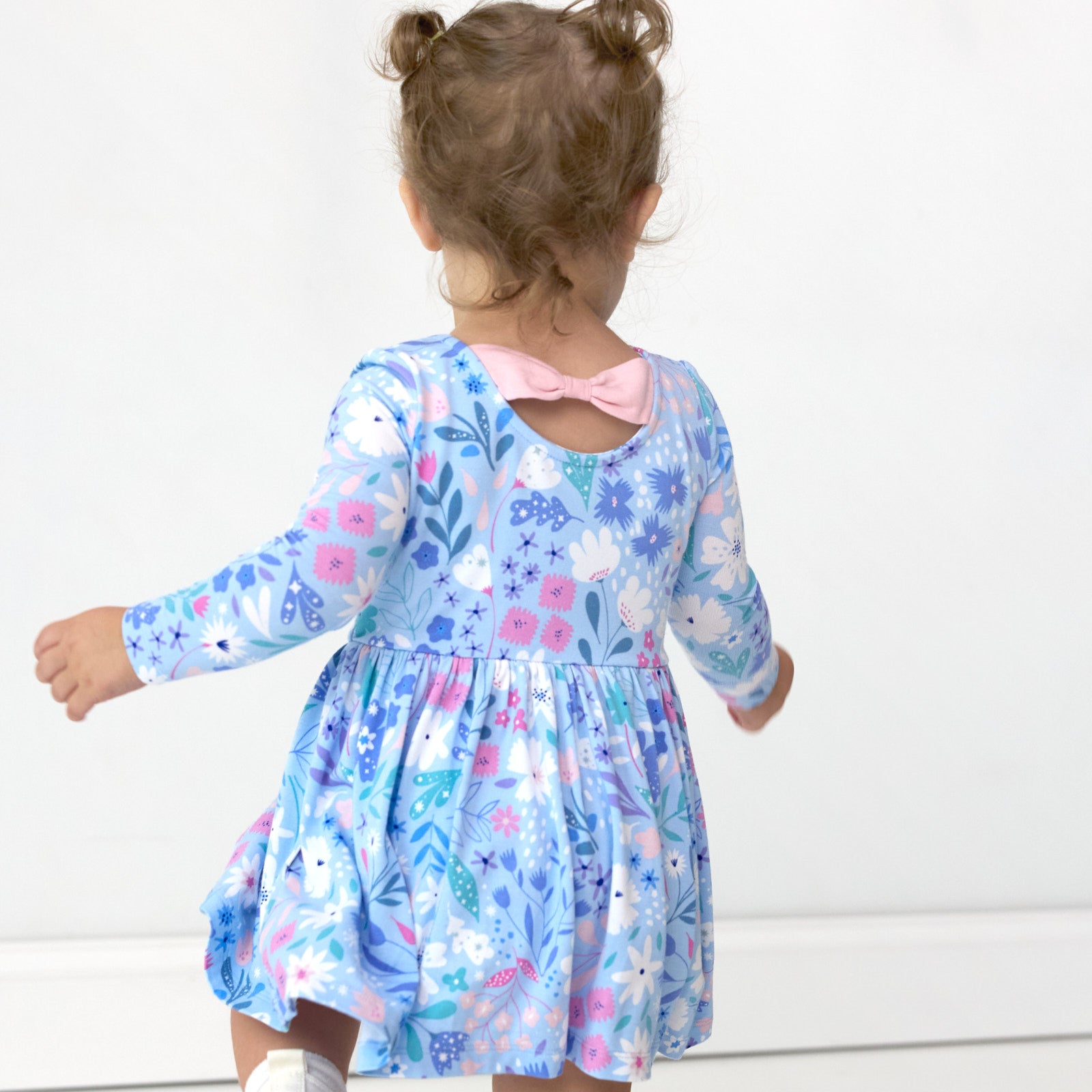 Image of girl showing the back detail on the Magical Meadow Bow Back Skater Dress with Bodysuit