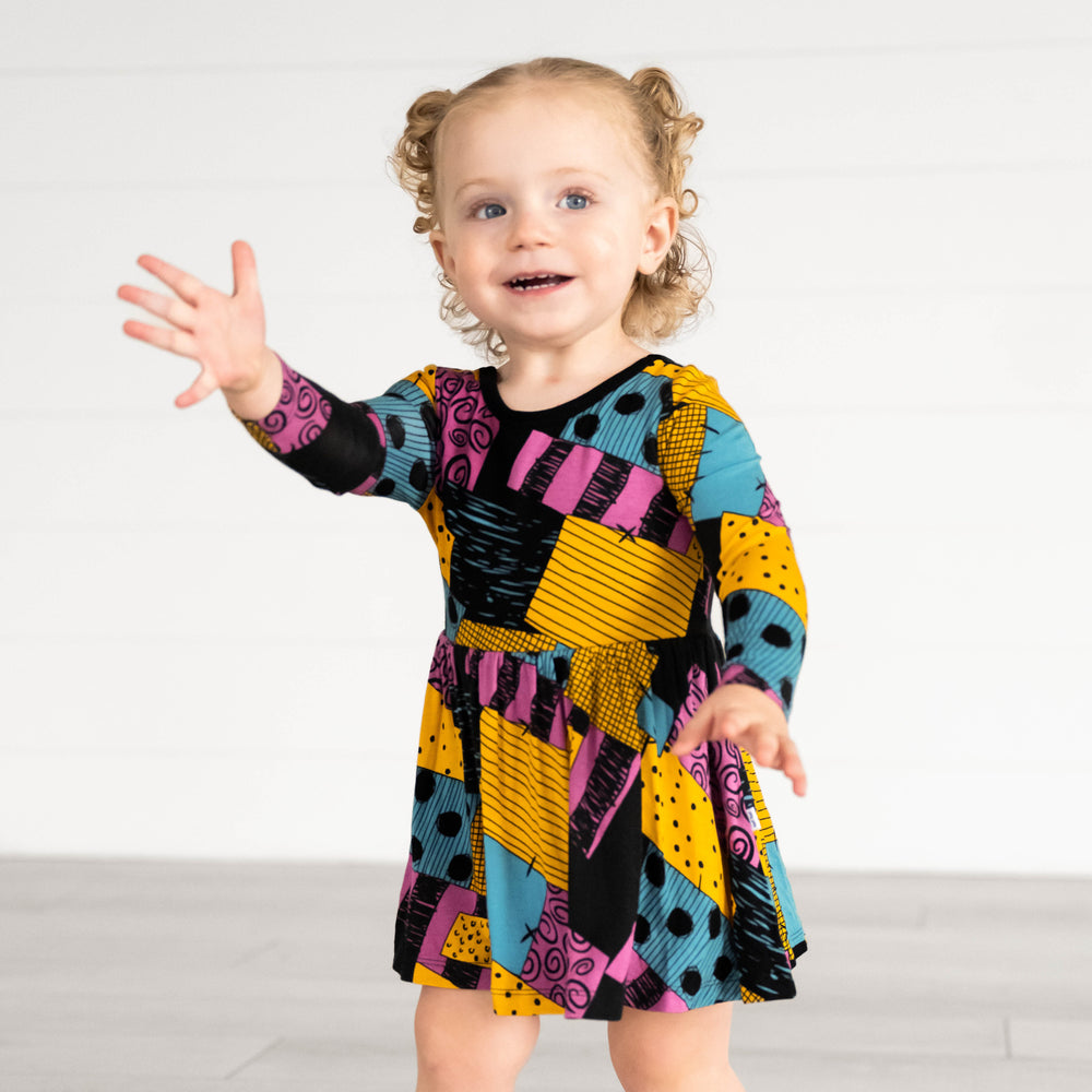 Girl posing while wearing the Disney Sally's Patchwork Twirl Dress with Bodysuit