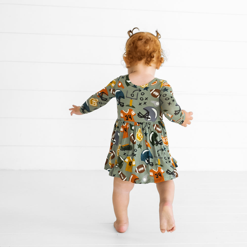 Back view image of a child wearing a Touchdown Time Twirl Dress with Bodysuit