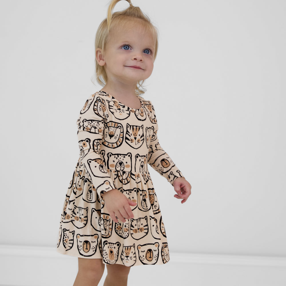 Child wearing a Lions, Tigers & Bears long sleeve skater dress with bodysuit featuring black and tan animal illustrations