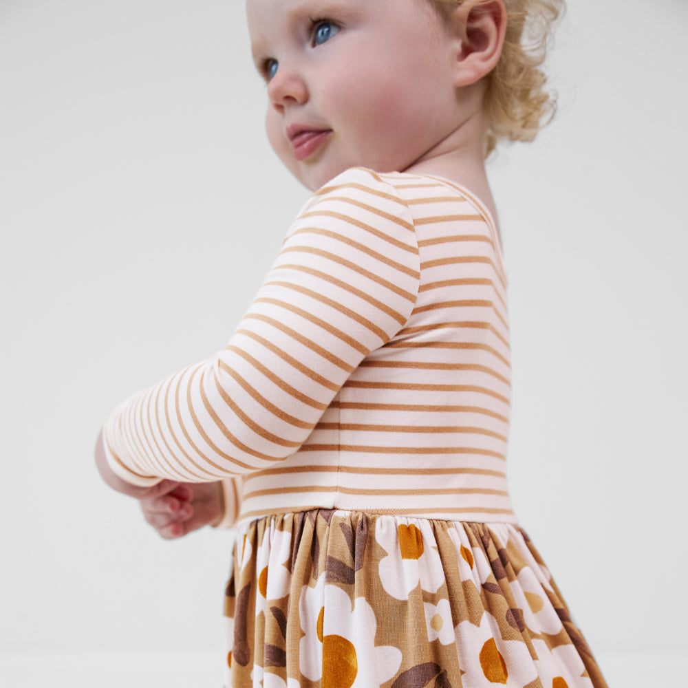 Close-up side view of a child wearing a Daisy Daydream long sleeve twirl dress with bodysuit