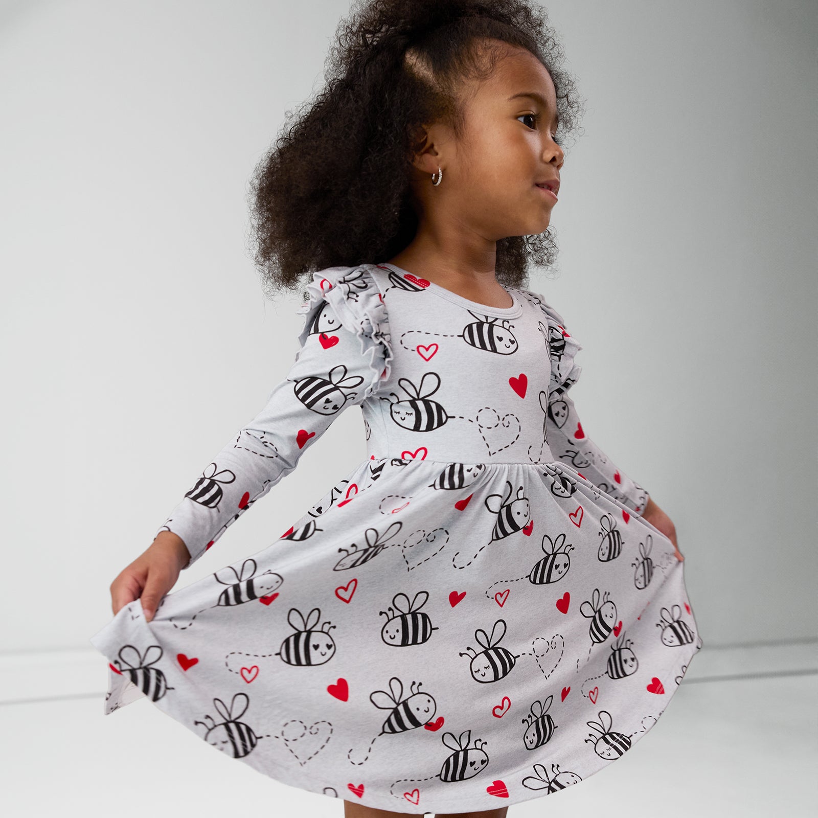 child holding out the sides of a bee mine flutter twirl dress