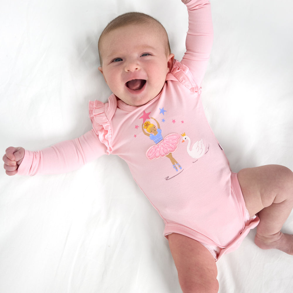 Top view image of smiling baby laying down while wearing the Prima Pink Flutter Bodysuit